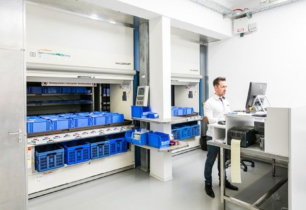 A warehouse with automated shelving systems and a person working on a computer.