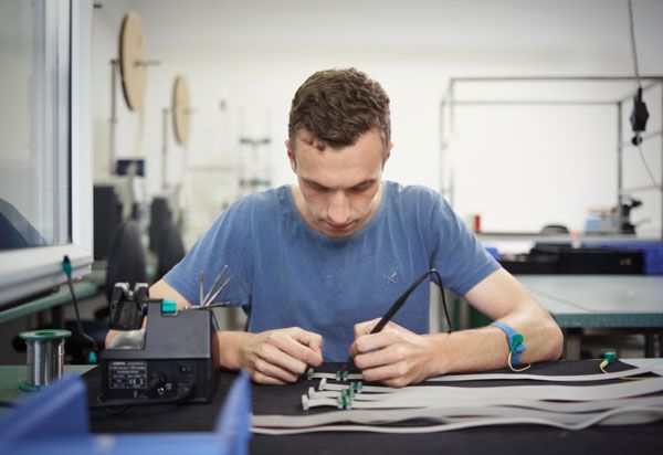 A technician soldering or working on a circuit board with tools.