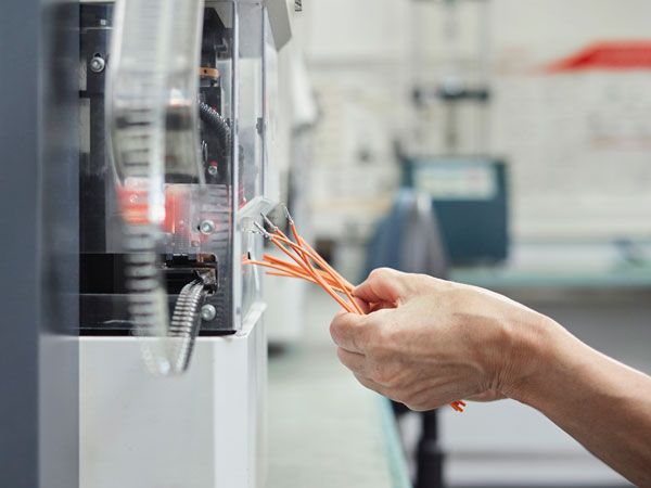 A close-up of a hand inserting wires into a machine.